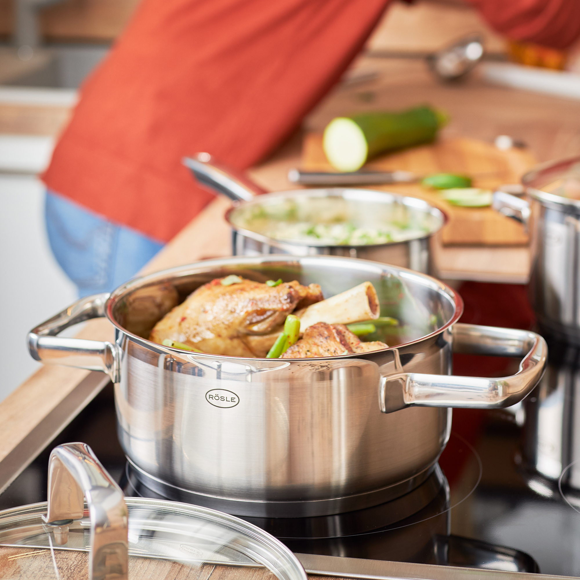 RÖSLE roasting pan 20 cm with chicken and vegetables Roasting pan, 20 cm, stainless steel, with chicken pieces and vegetables on the hob.