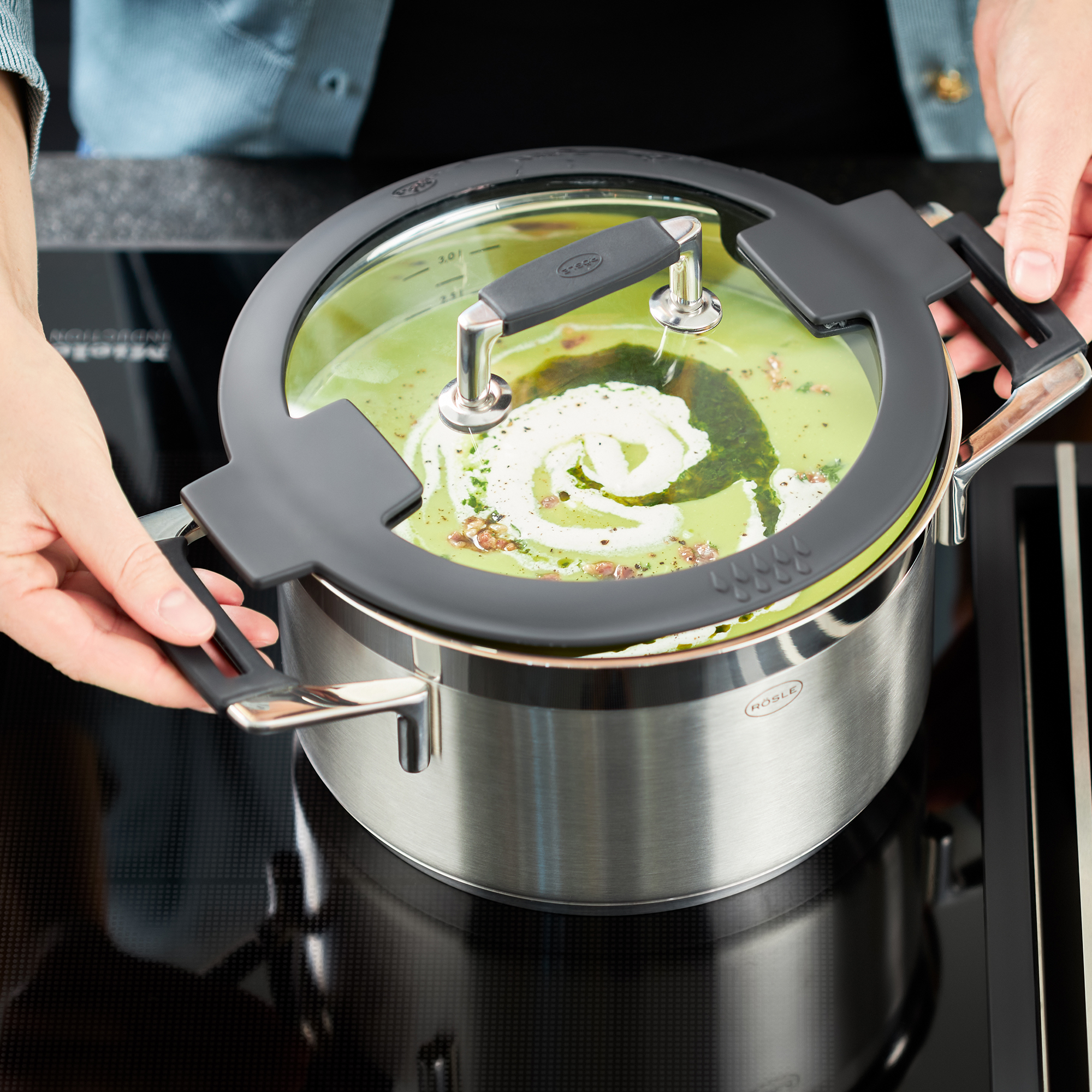 RÖSLE Kochtopf 16 cm mit Glasdeckel Kochtopf 16 cm aus Edelstahl mit Glasdeckel, auf einem Herd, mit grünem Inhalt.