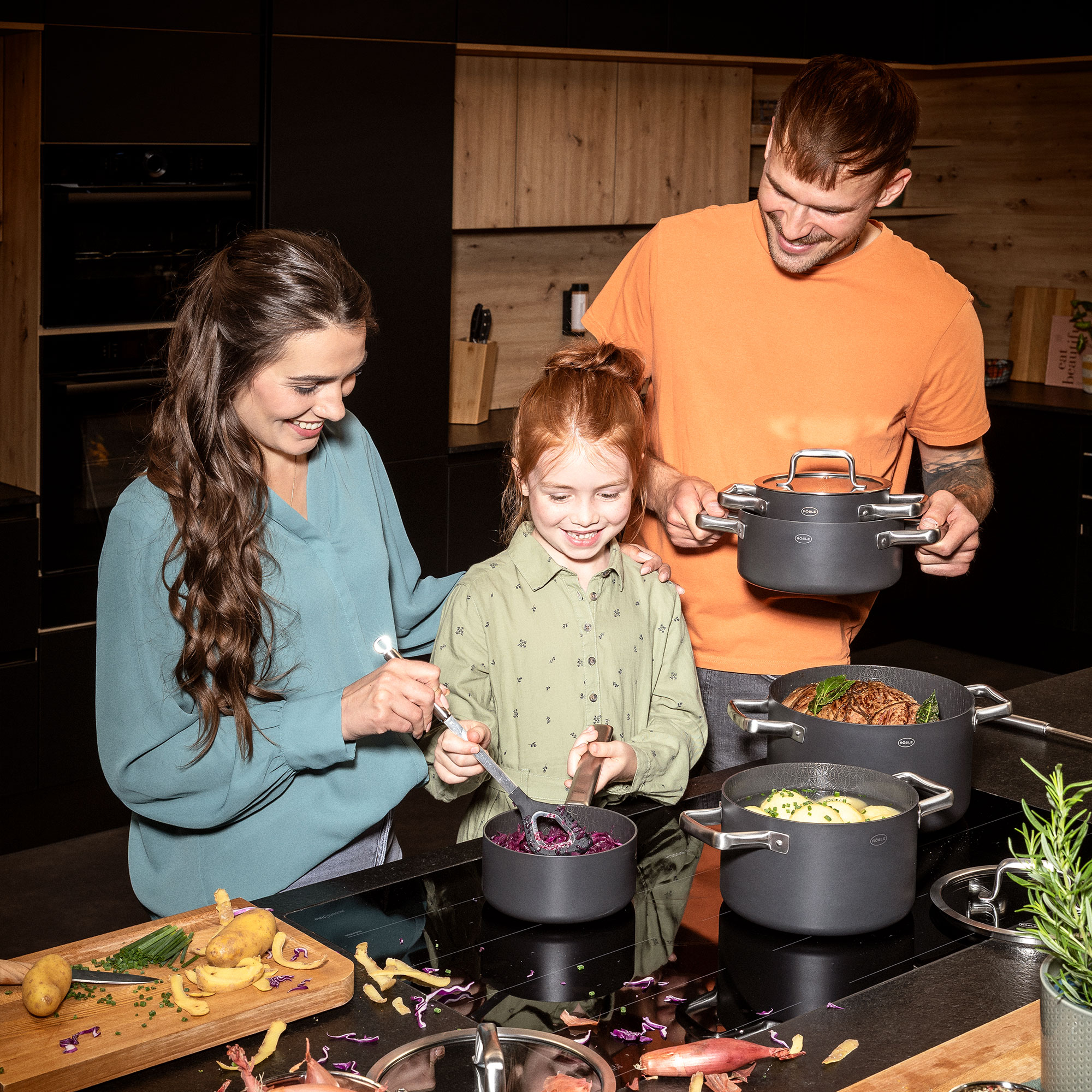 Vater, Mutter und Tochter kochen zusammen mit den EBONIC Pfannen in einer Küche