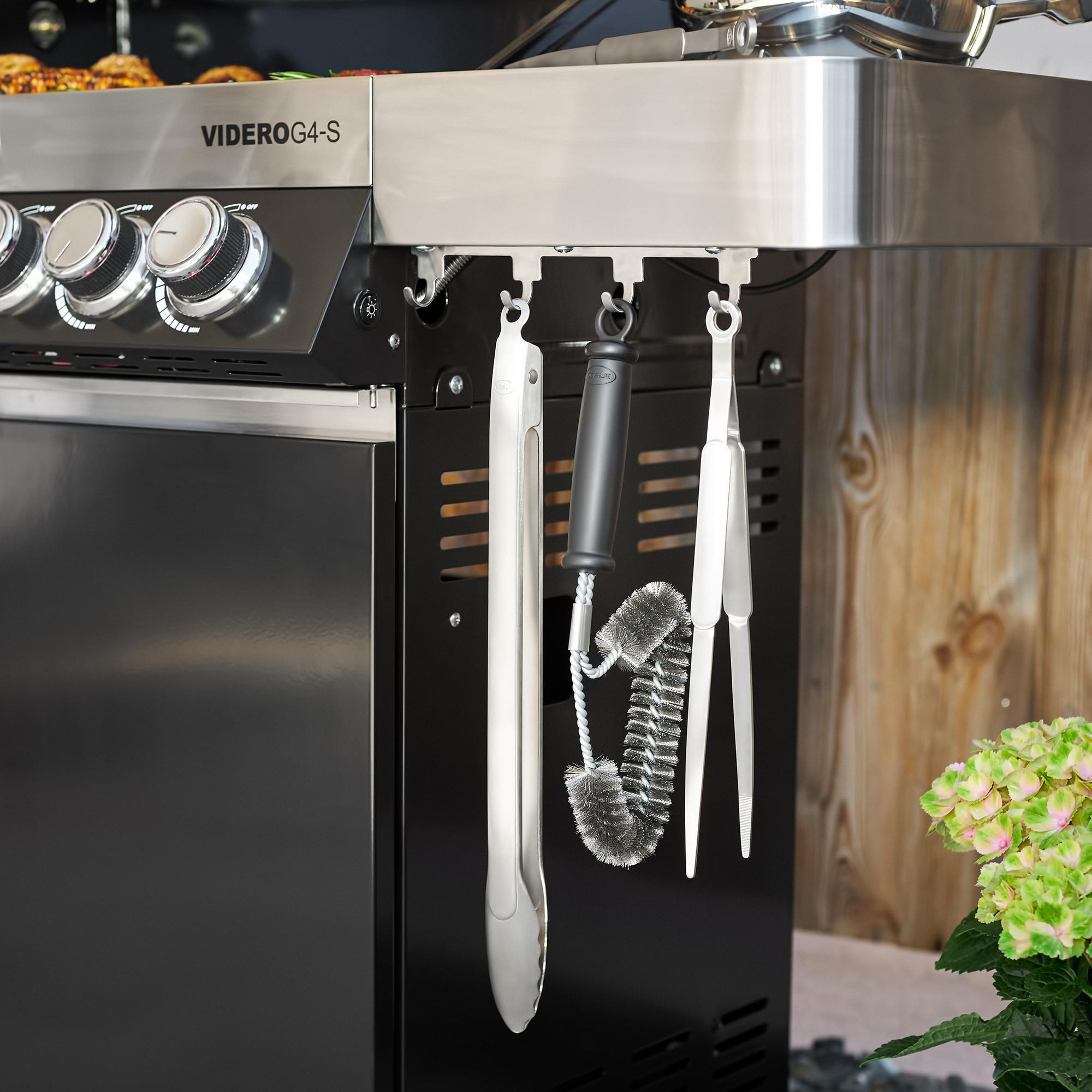 RÖSLE barbecue tongs and barbecue accessories Stainless steel barbecue tongs, 40 cm long, hanging on a barbecue, next to a barbecue brush...