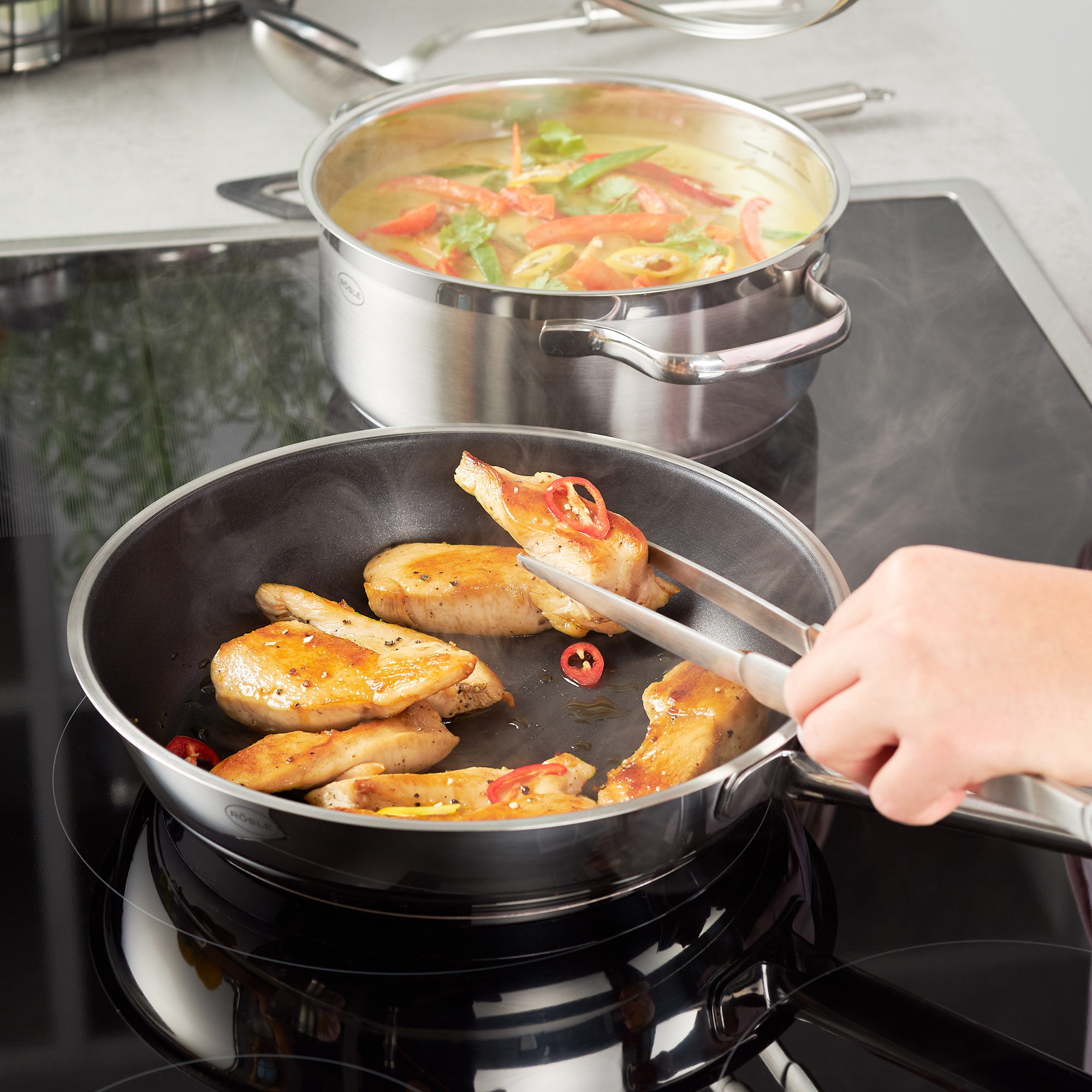 RÖSLE needle nose tongs for cooking Stainless steel pointed tongs, 31 cm, used to turn fried chicken pieces in a pan.