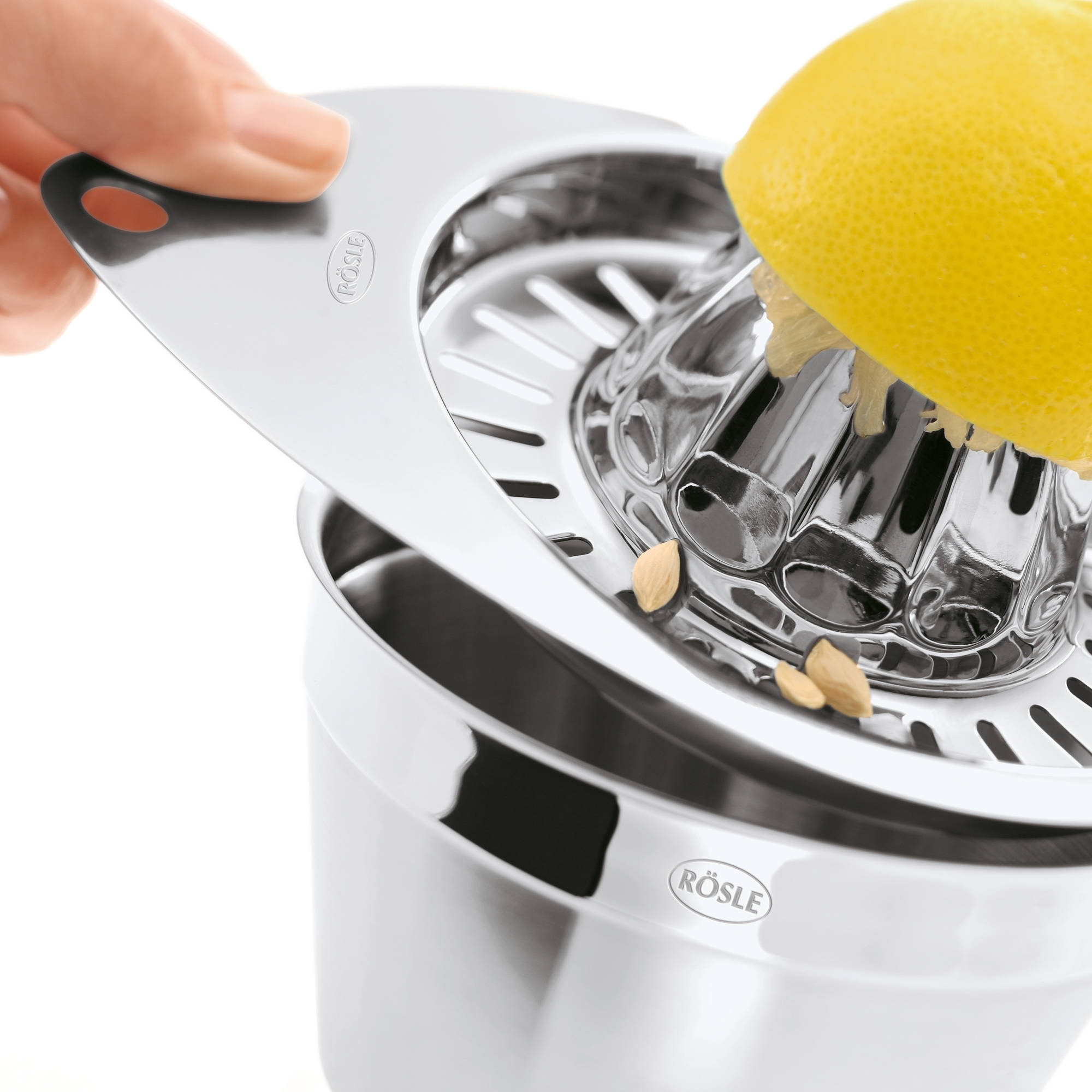RÖSLE lemon squeezer Stainless steel lemon squeezer with a halved lemon held above the squeezer.