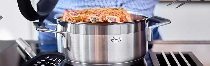 Roestvrijstalen braadslede met een schaal erin, geplaatst op een kookplaat.