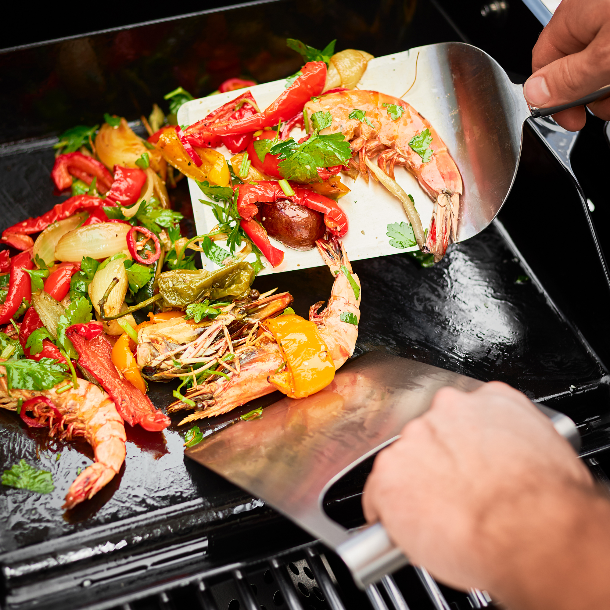 RÖSLE plancha all-purpose spatula with prawns and vegetables Plancha all-purpose spatula lifts grilled prawns and vegetables on a grill plate.