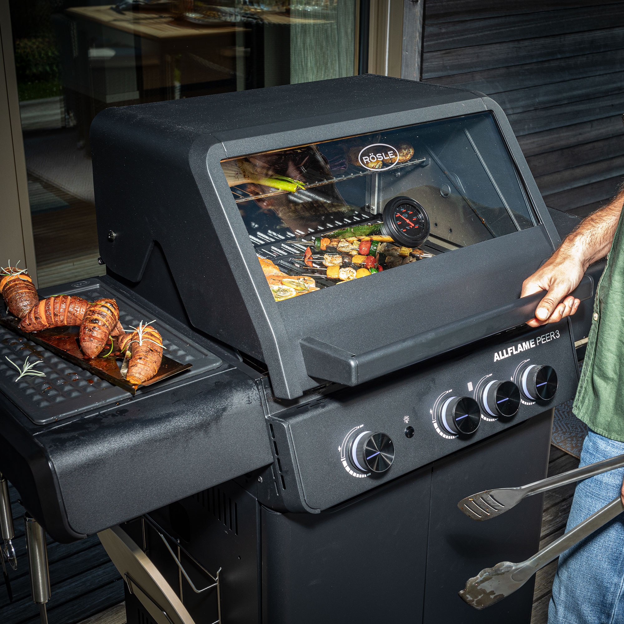 RÖSLE Allflame Peer3 Gasgrill Allflame Peer3 Gasgrill mit Grillgut auf dem Rost und einer Grillplatte, Bedienung durch eine...