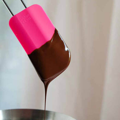 Schokolade läuft von dem Pink Charity Teigschaber breit