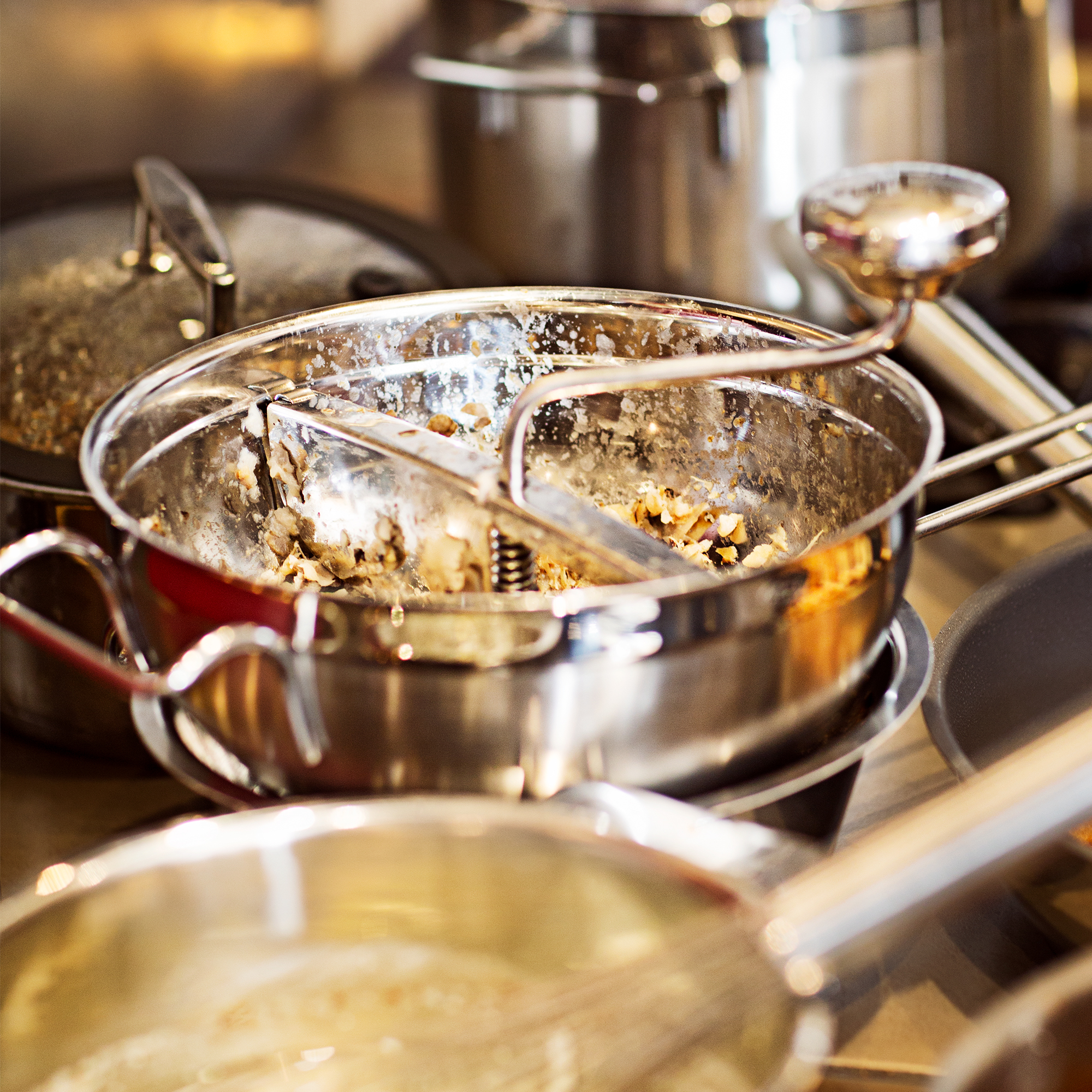 RÖSLE Passetout mit Gegengriff Passetout mit Gegengriff aus Edelstahl, teilweise mit Essensresten, auf einer Arbeitsfläche.