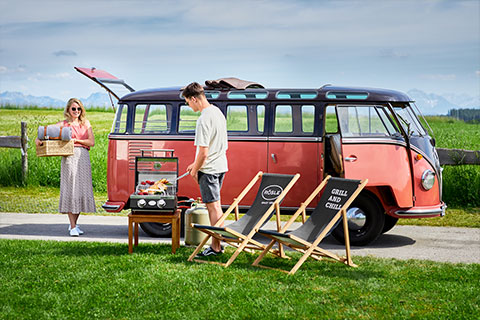 Couple grilling in front of VW Bully with the portable grill.