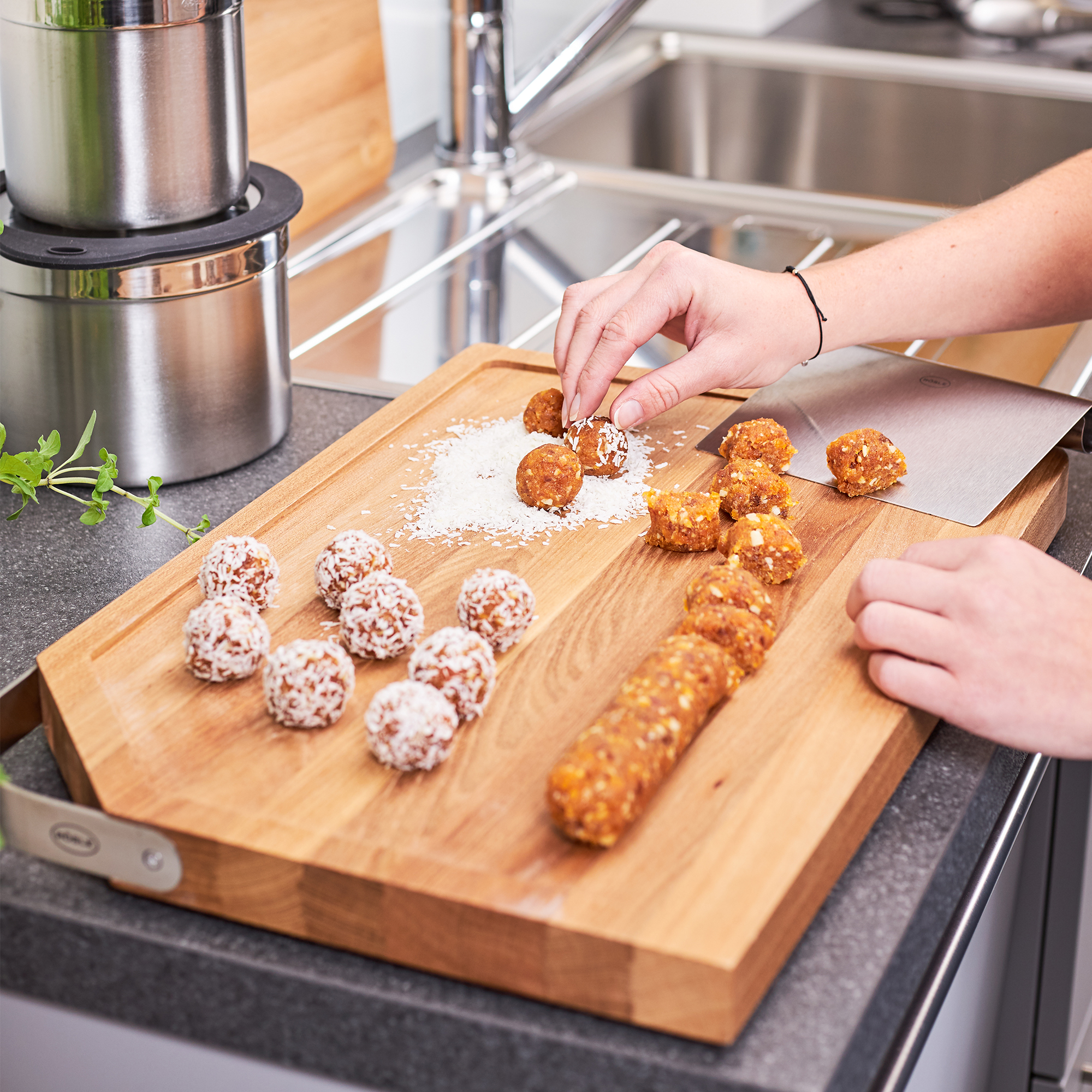 Holz Schneidbrett mit Energiebällchen Schneidbrett aus Holz, auf dem verschiedene Energiebällchen und eine längliche Rolle liegen,...