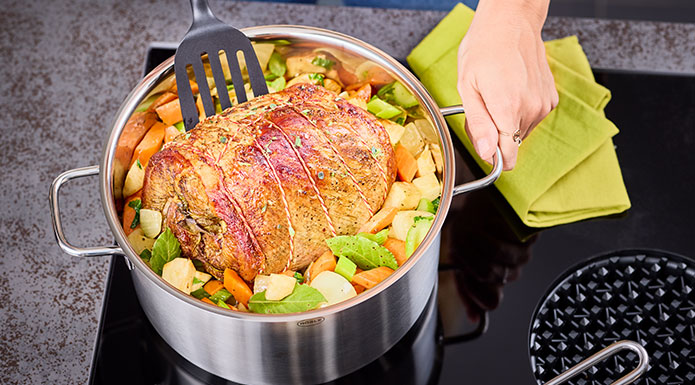 Spatula turns roast in cooking pot