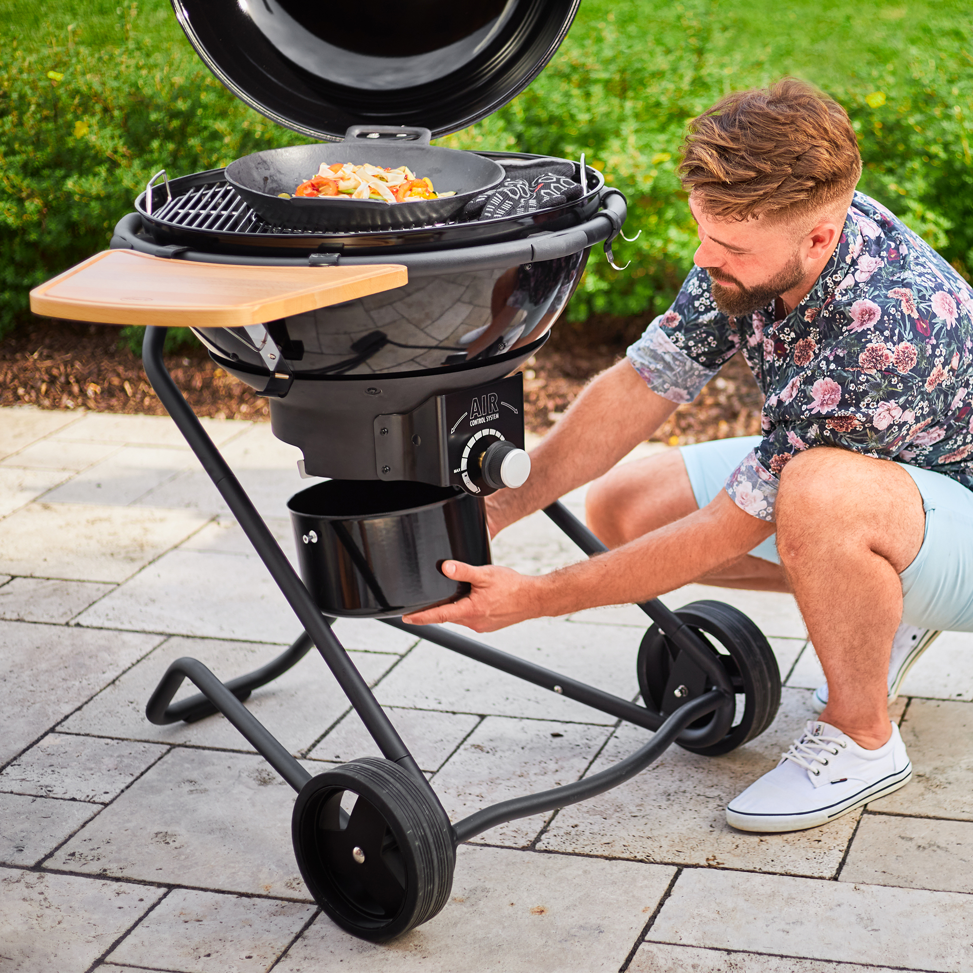 RÖSLE Holzkohle Kugelgrill No1 AIR F60 Holzkohle Kugelgrill No1 AIR F60 in Schwarz, mit einem Mann, der das Grillzubehör anpasst.