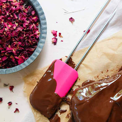 Teigschaber Pink Charity mit Schokoladenkuvertüre liegt neben Brownies