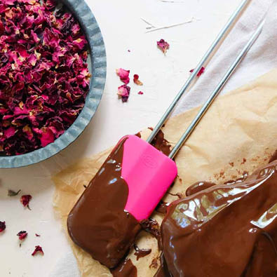 Dough scraper Pink Charity with chocolate coating lies next to brownies