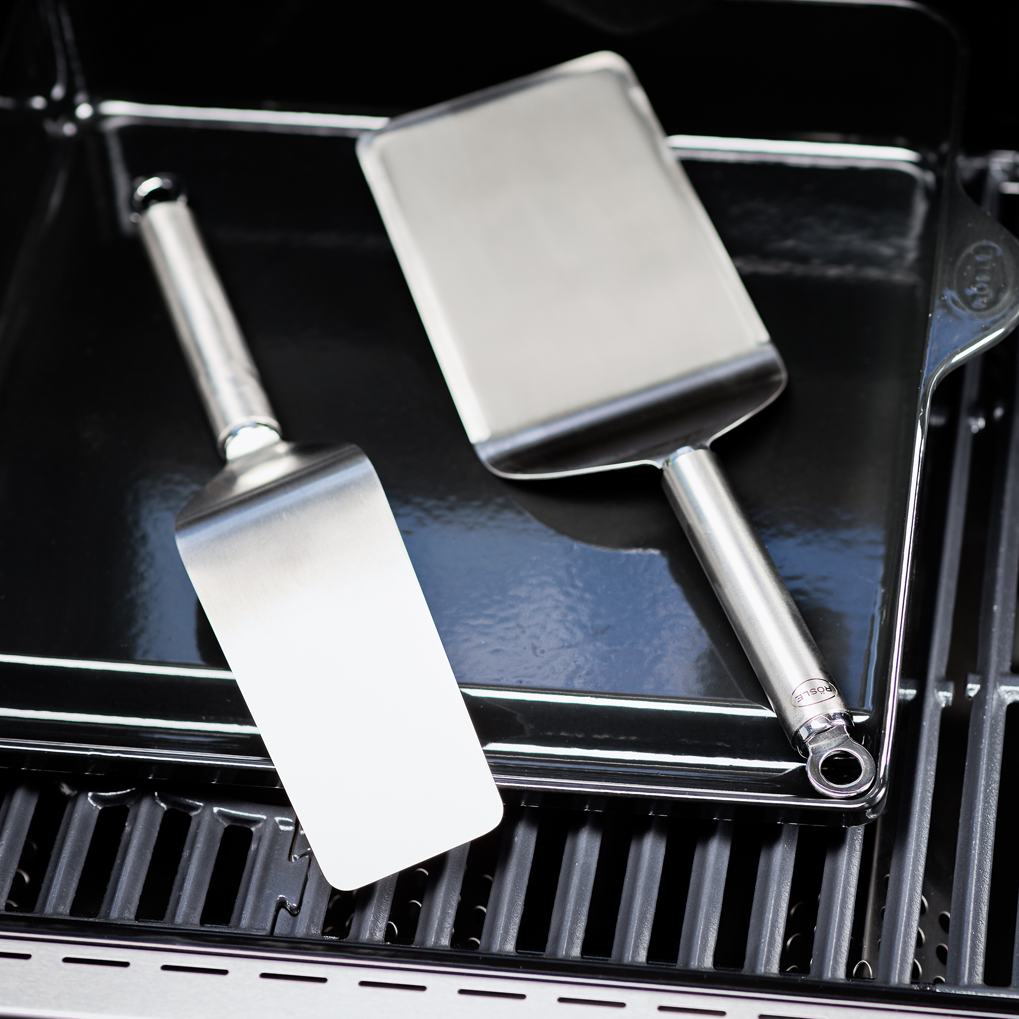 RÖSLE stainless steel plancha spatula Plancha spatula, two wide stainless steel spatulas, on a grill plate.