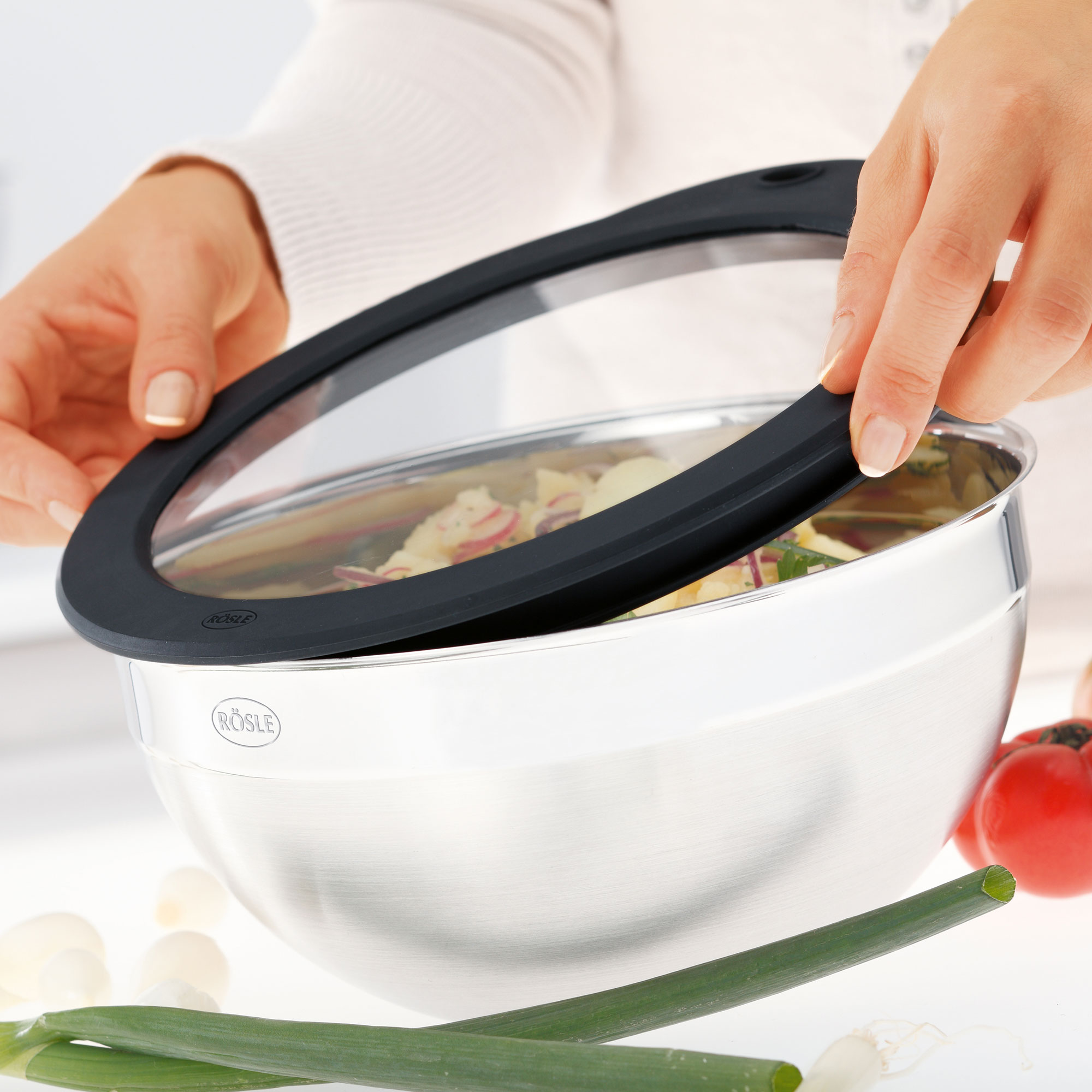 RÖSLE Salatschleuder mit Frischhaltedeckel Salatschleuder aus Edelstahl mit Frischhaltedeckel, eine Person setzt den Deckel auf die Schüssel.