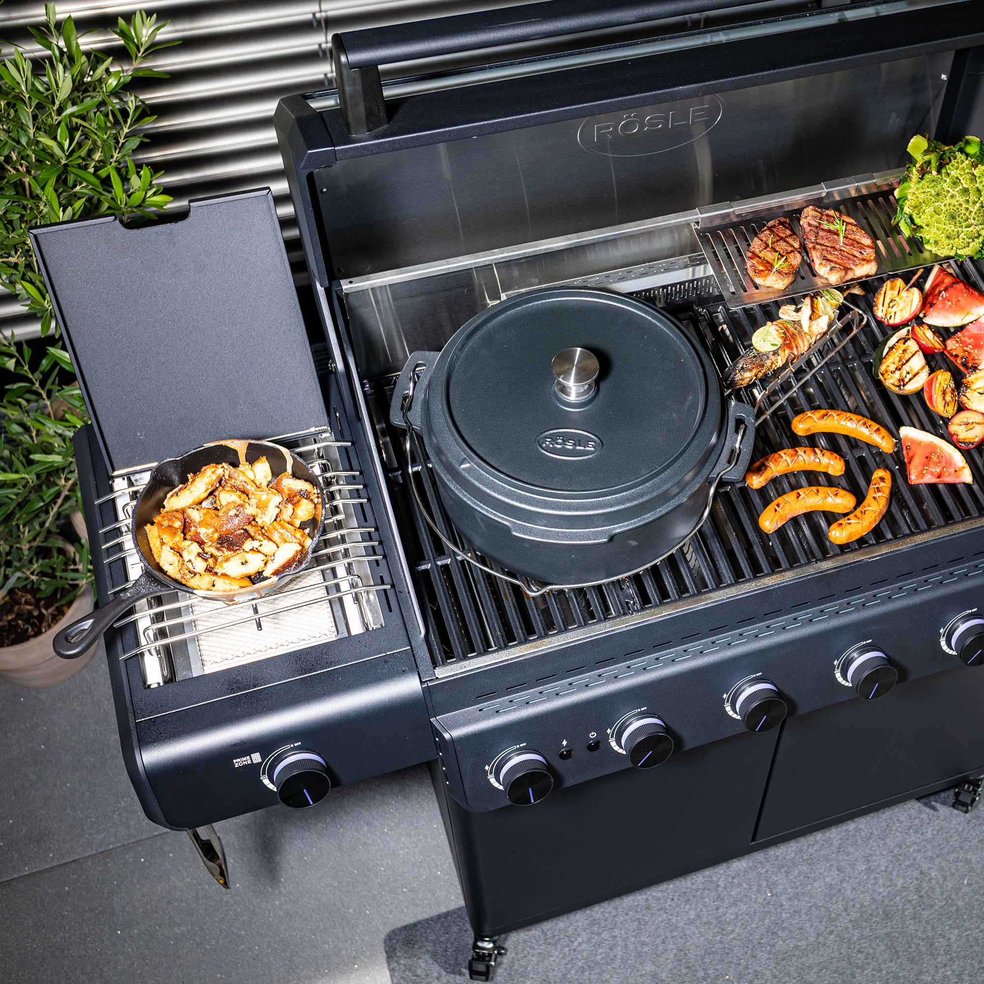 RÖSLE Bratpfanne Gusseisen Auf einem RÖSLE Grill werden mehrere Lebensmittel angebraten. Einige dieser Lebensmittel werden...