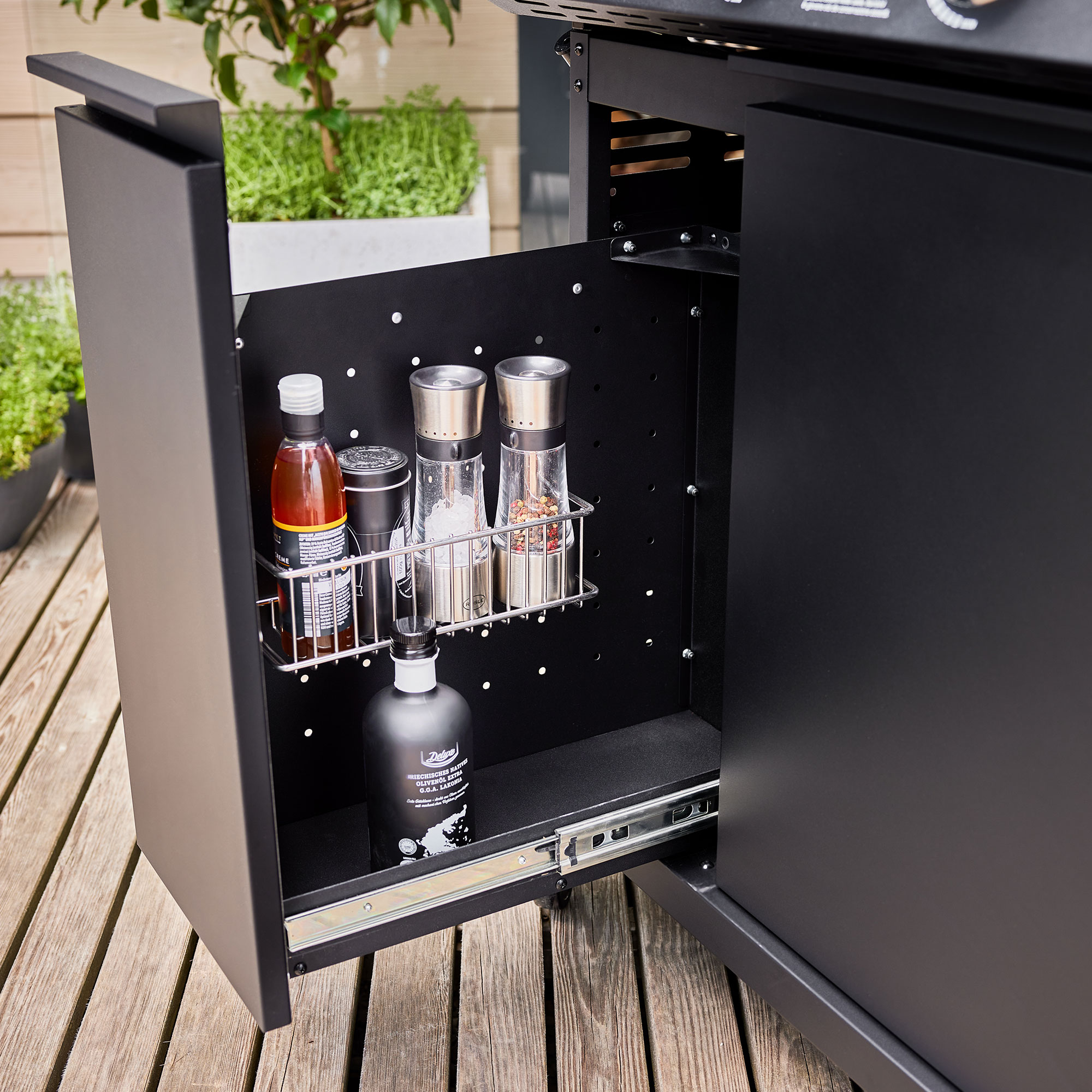 Gasgrill Videro G3-S PRO mit offenem Unterschrank, der Gewürz- und Flaschenhalter zeigt.