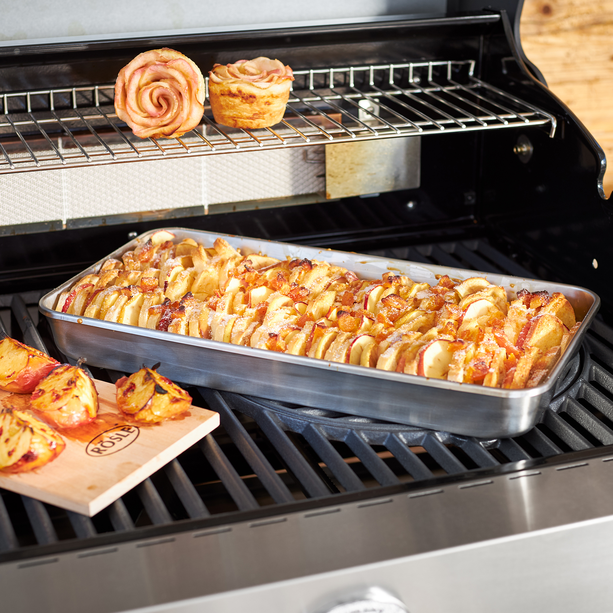 RÖSLE Edelstahl Universalschale auf dem Grill Edelstahl Universalschale mit gegrillten Kartoffeln und Apfelrosen auf einem Grillrost.