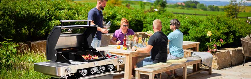 Familie am Tisch neben der Gasgrill BBQ-Station Videro G4-S