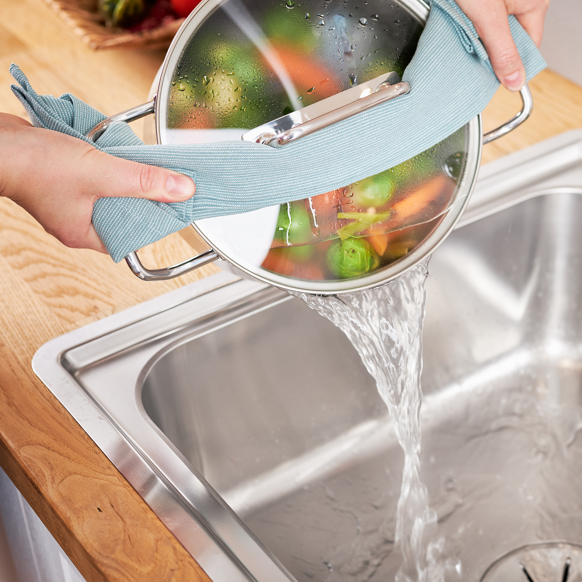 RÖSLE Gemüsetopf 24 cm beim Abgießen Gemüsetopf mit Glasdeckel, Wasser wird über die Spüle abgegossen, Hände halten den Topf mit...