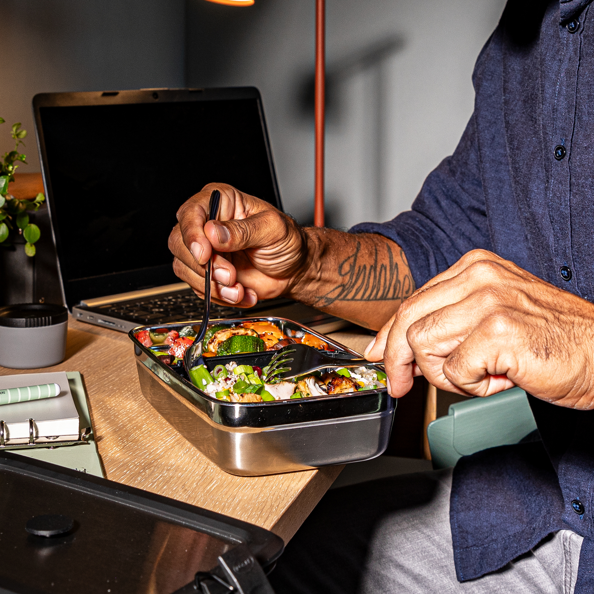 Flexx2go 1l Trennsteg-Bento-Box aus Edelstahl mit verschiedenen Lebensmitteln, Person mit Gabel beim Essen.