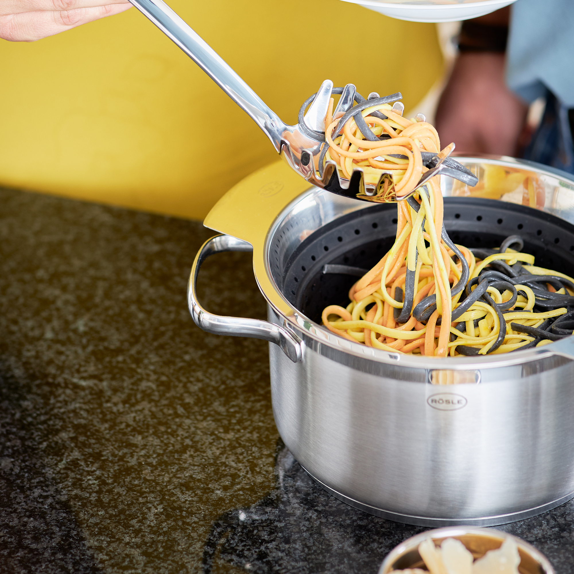 RÖSLE faltbarer Seiher mit Spaghetti faltbarer Seiher aus Edelstahl, schwarz, mit Spaghetti, die aus dem Sieb gehoben werden.