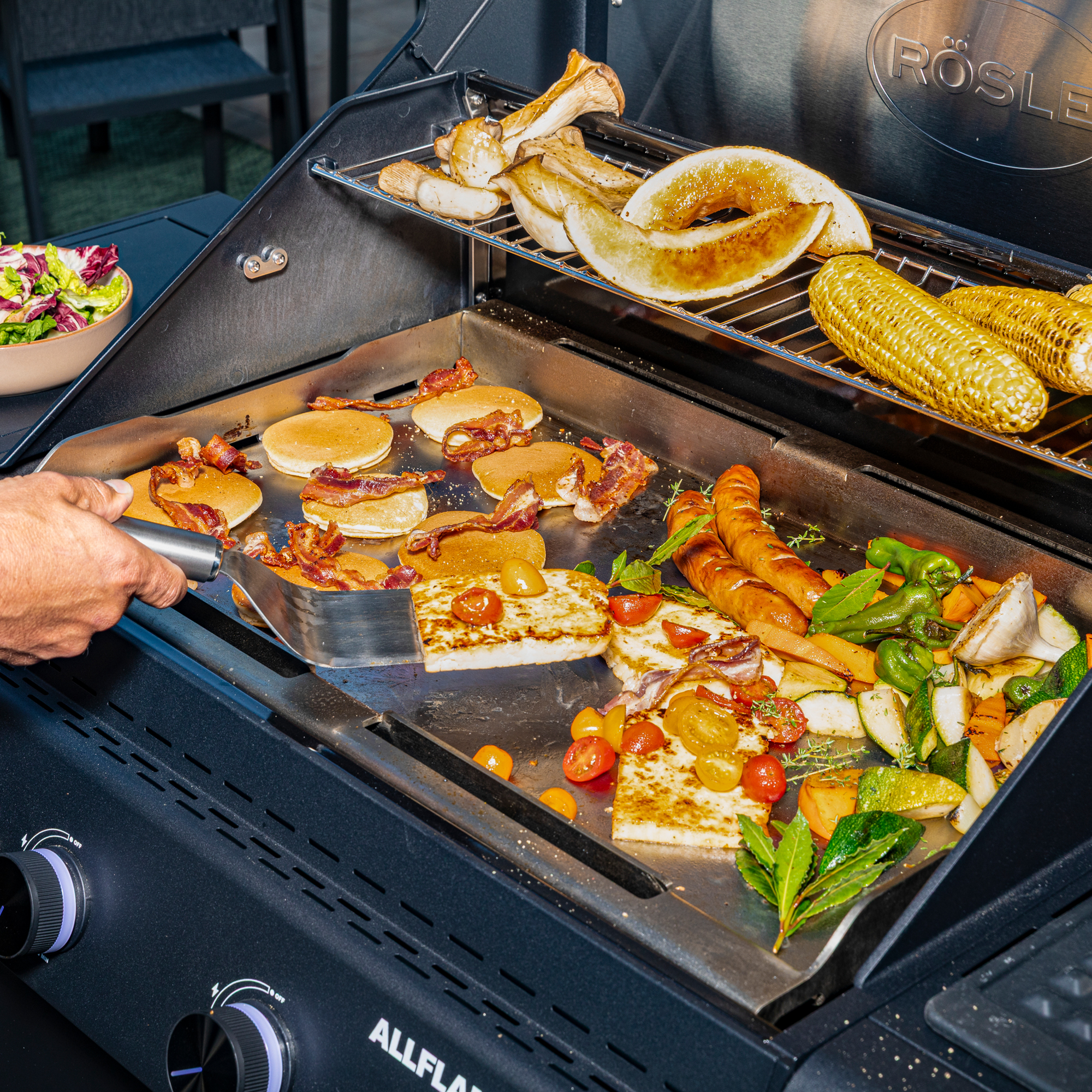 Grillkäse, Pancakes und Gemüse wird auf der Grillplatte gebraten.