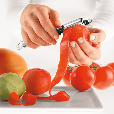 Tomate wird mit Schäler geschält
