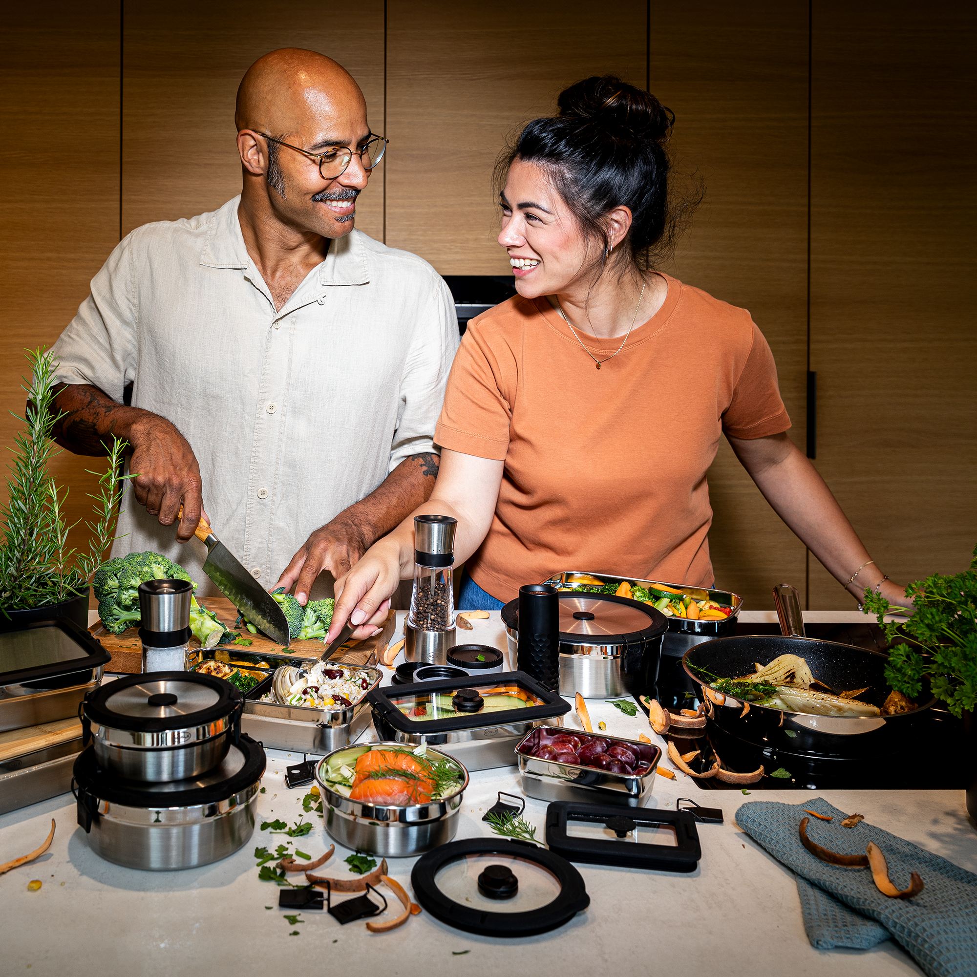 Küchenszene mit zwei Personen beim Kochen Zwei Personen in der Küche, die gemeinsam Gemüse schneiden und zubereiten, umgeben von Kochutensilien...