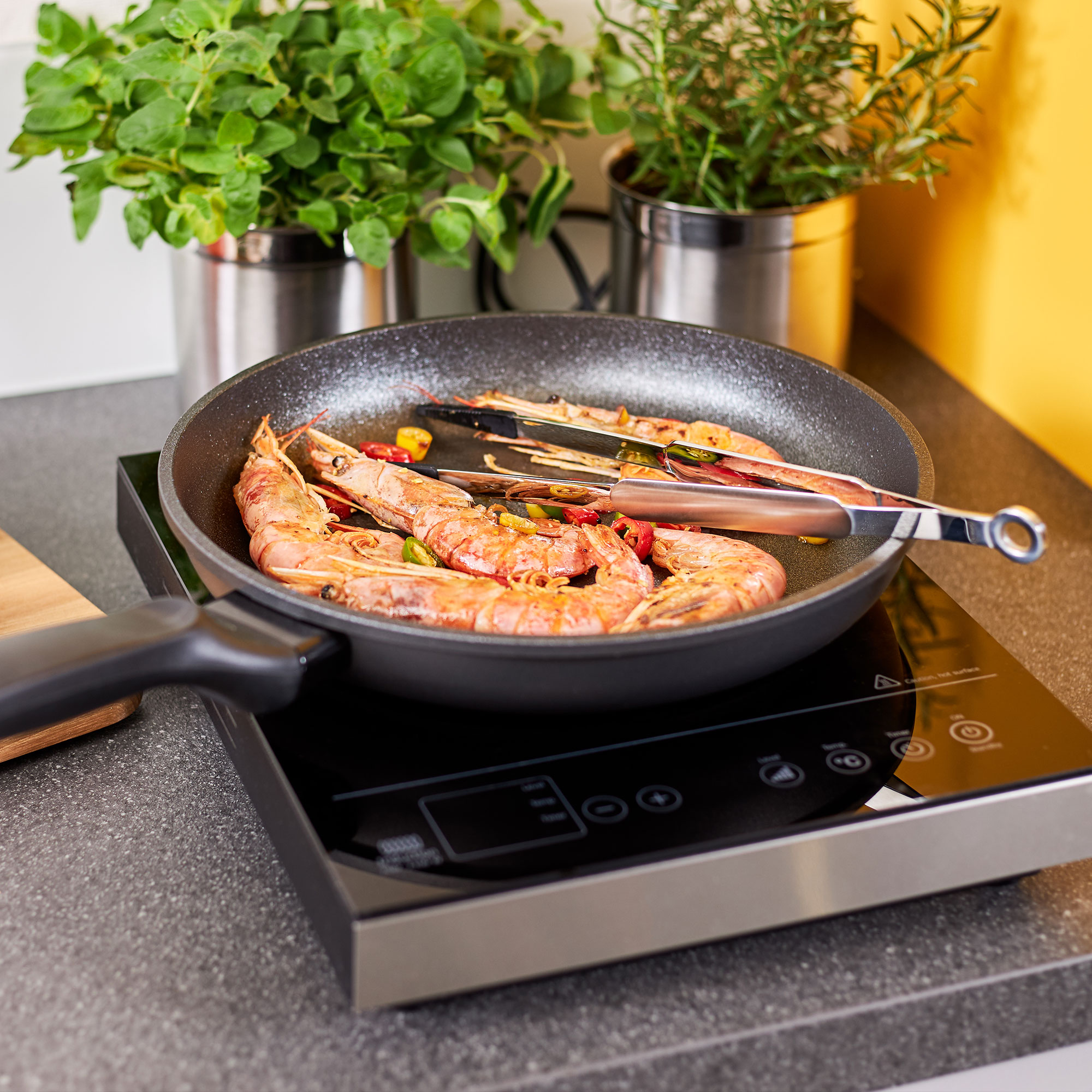 RÖSLE pointed tongs in action with prawns Stainless steel pointed tongs in a pan with prawns and vegetables on an induction hob.