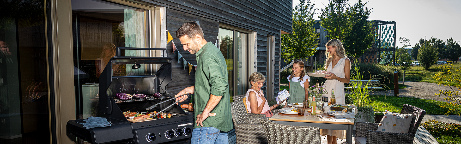 Kooperationen Vater grillt und Kinder und Frau decken den Tisch