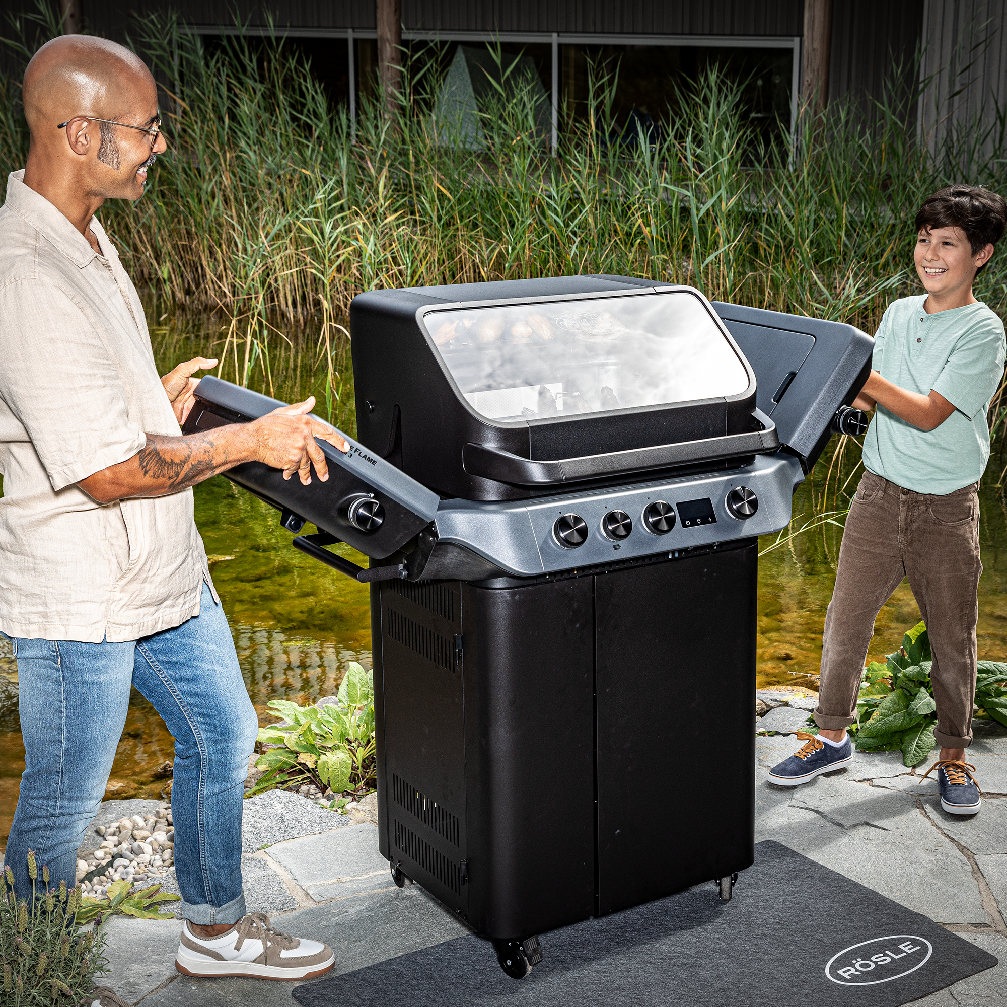 Blazeflame Master Grill, schwarz, mit zwei Personen, die die Klappen öffnen, im Freien.