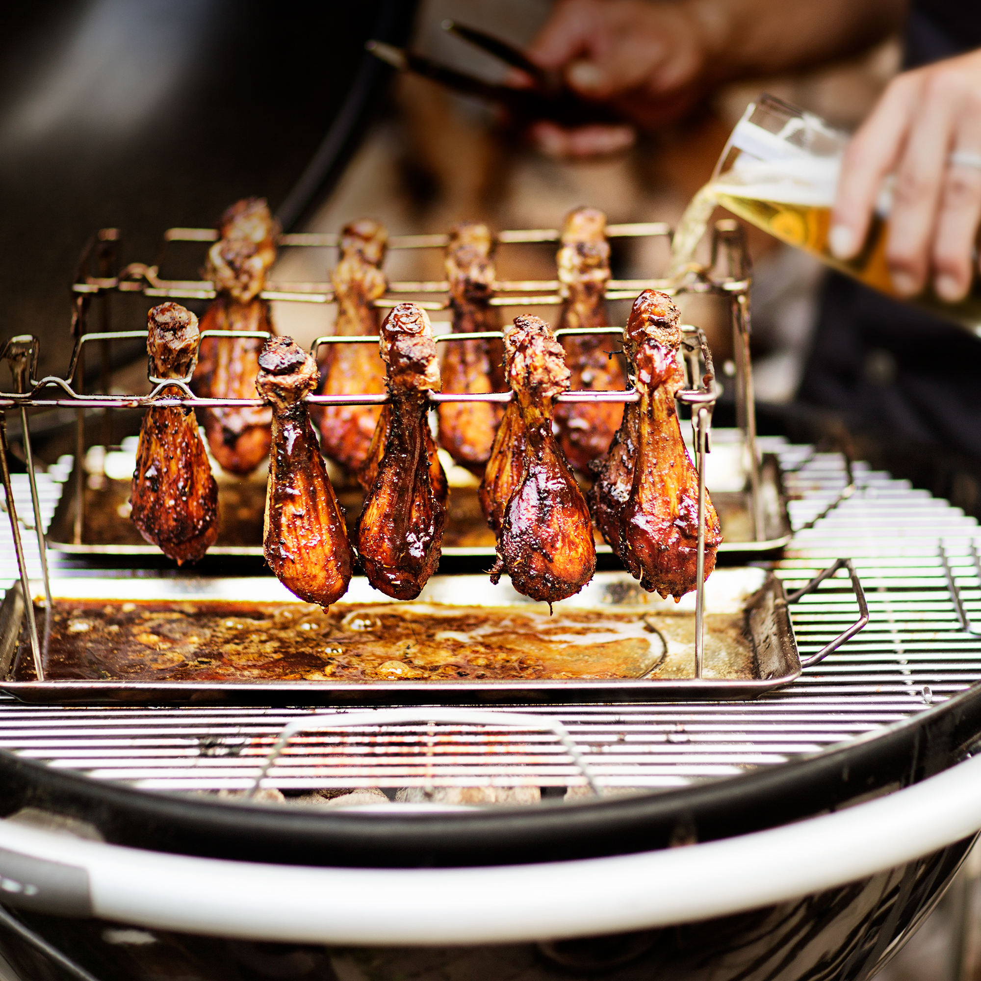 Chicken rack from RÖSLE with grilled chicken thighs Chicken rack with grilled chicken thighs on a grill while beer is poured in.