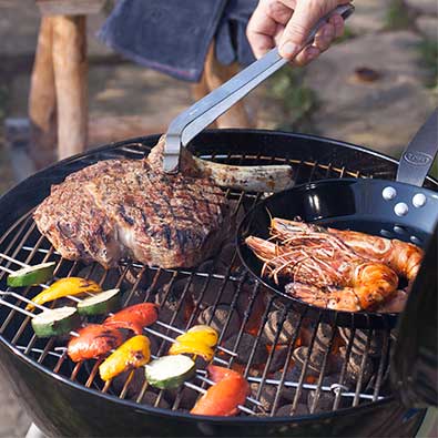 Charcoal kettle grill with steak and vegetable skewers