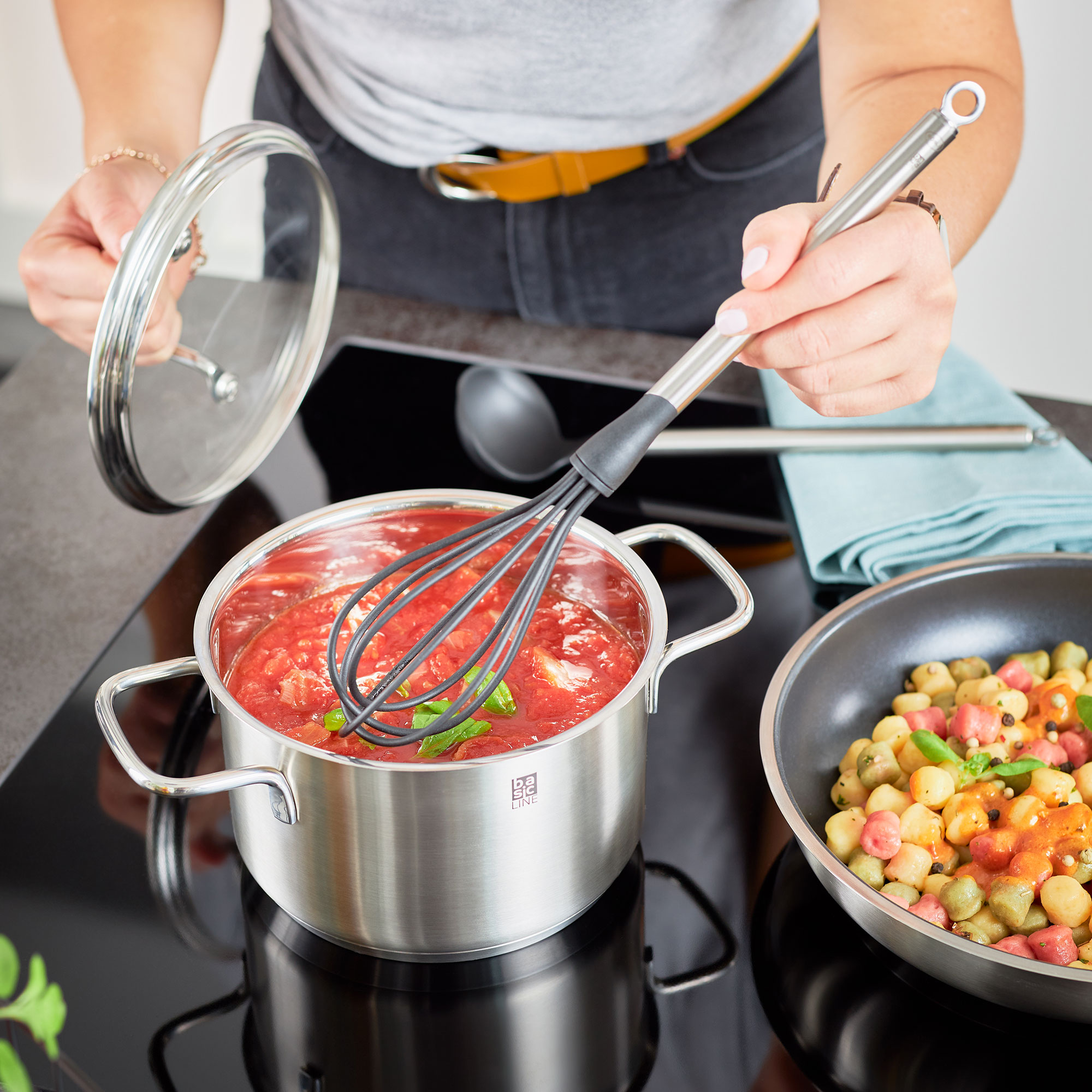RÖSLE Gourmet-Set in der Anwendung Gourmet-Set: Eine Person rührt mit einem Schneebesen in einem Topf mit Tomatensauce auf einem...