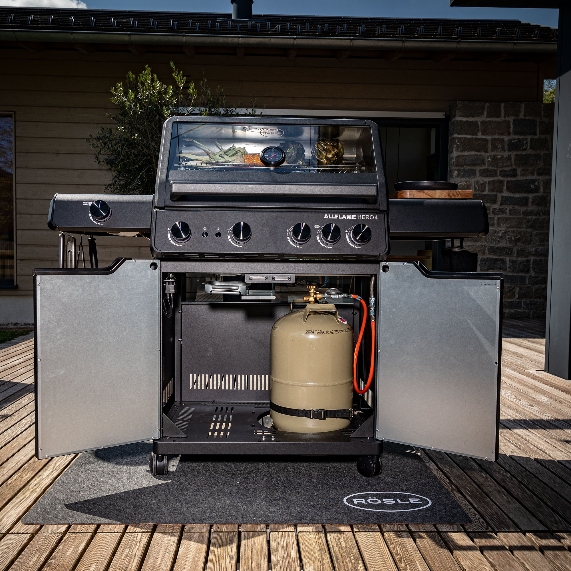 RÖSLE Allflame Hero4 Gasgrill Allflame Hero4 Gasgrill mit geöffneten Türen und Gasflasche im Inneren, auf einer Holzterrasse.