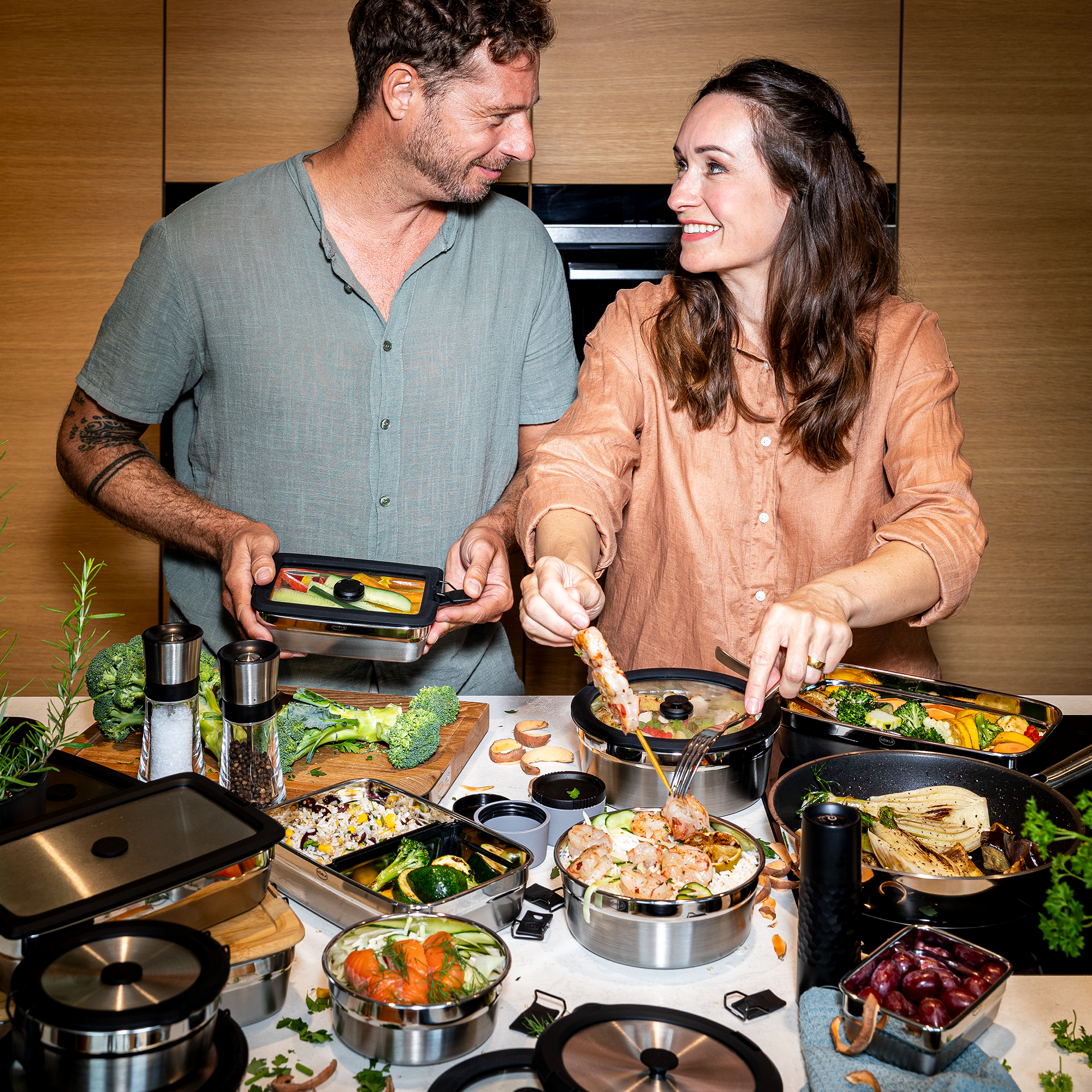 Paar in der Küche, das gemeinsam mit Behältern kocht und Gemüse zubereitet.