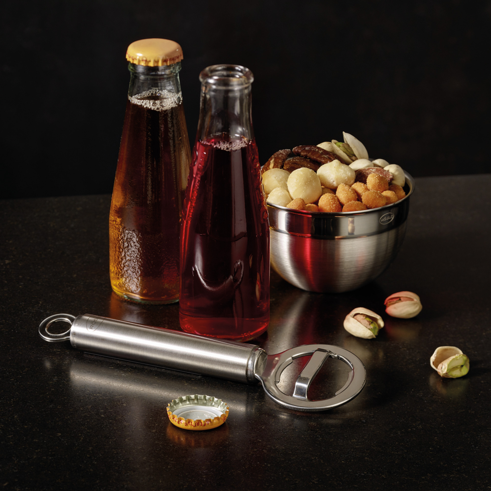 RÖSLE bottle opener and snacks Stainless steel bottle opener, next to two bottles of drinks and a bowl of snacks.