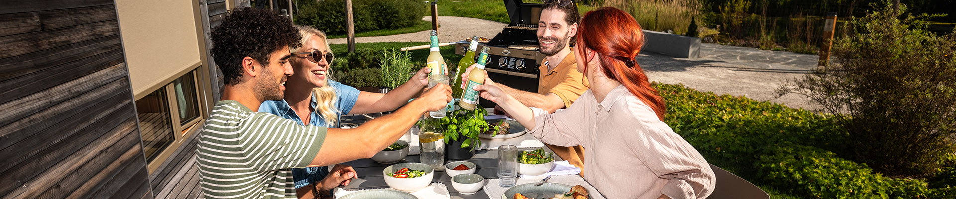 Geselliges Grillen mit Freunden Gruppe von fünf Personen, die beim Grillen an einem Tisch anstoßen, umgeben von frischen Zutaten...