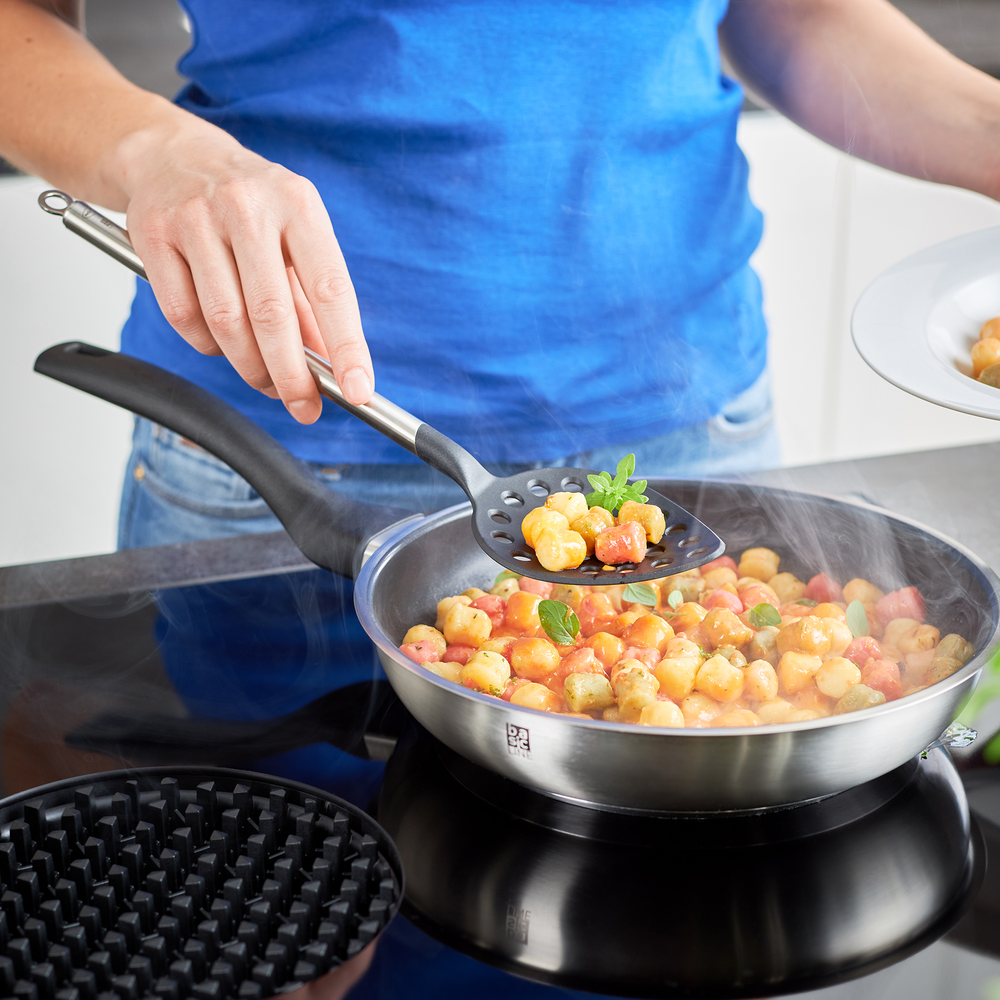 RÖSLE Bratpfanne 28cm mit Gemüse Bratpfanne aus Edelstahl mit Antihaftbeschichtung, eine Person hebt mit einem Pfannenwender...