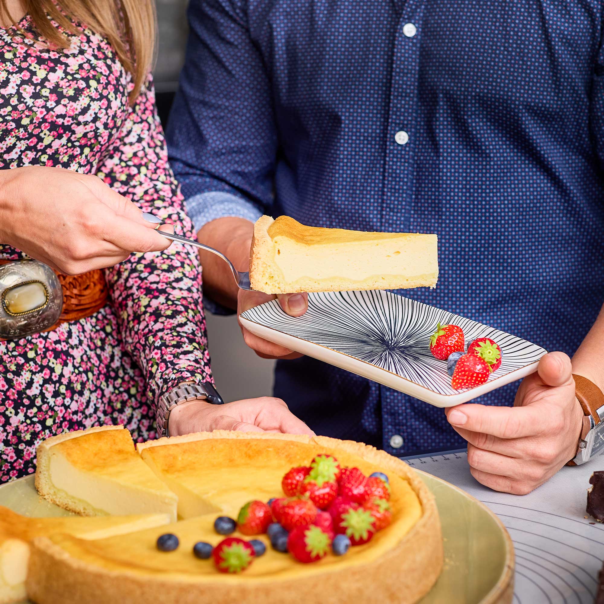 RÖSLE Tortenschaufel mit Käsekuchen Tortenschaufel hebt ein Stück Käsekuchen mit Beeren auf einen Teller.
