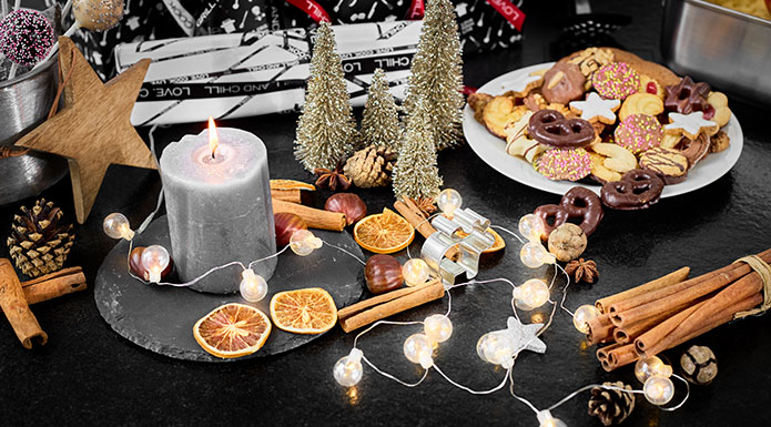 Plätzchen, Kerzen und Weihnachtsdekoration auf dem Tisch