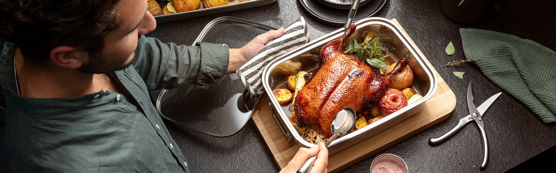 Bräter mit gebratenem Hähnchen Bräter mit gebratenem Hähnchen und Gemüse, Mann serviert das Gericht.