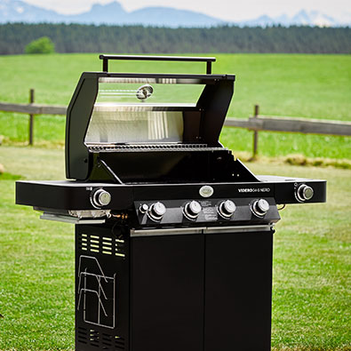 Gas grill Videro G4-S NERO with open lid in the garden.