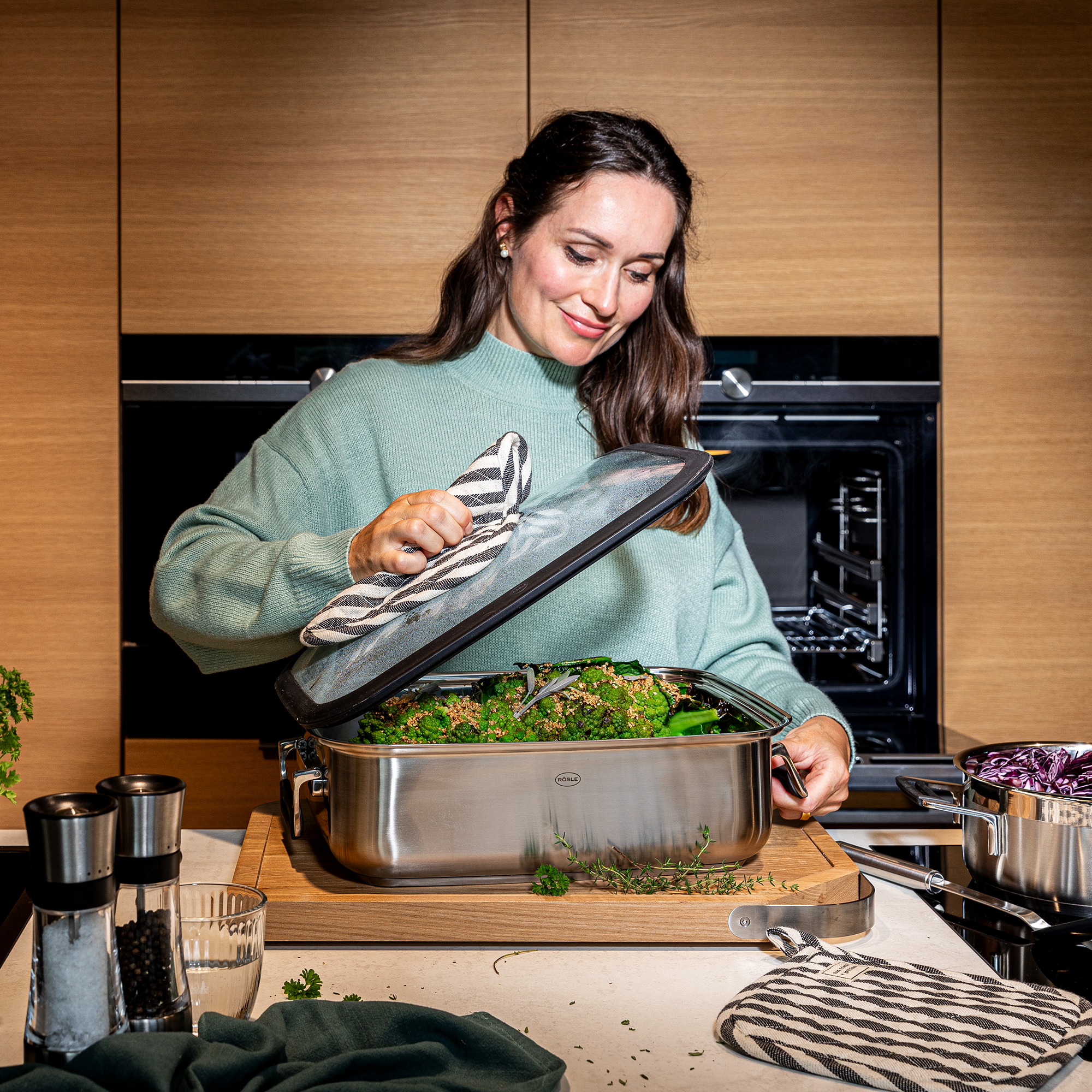 RÖSLE Bräter Silence Pro mit Gemüse Bräter Silence Pro aus Edelstahl, eine Frau hebt den Deckel und zeigt Gemüse darin.