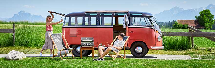 Gas barbecue BBQ Portable Videro G2-P Couple with VW bus and gas barbecue BBQ-Portable Videro G2-P at the grill