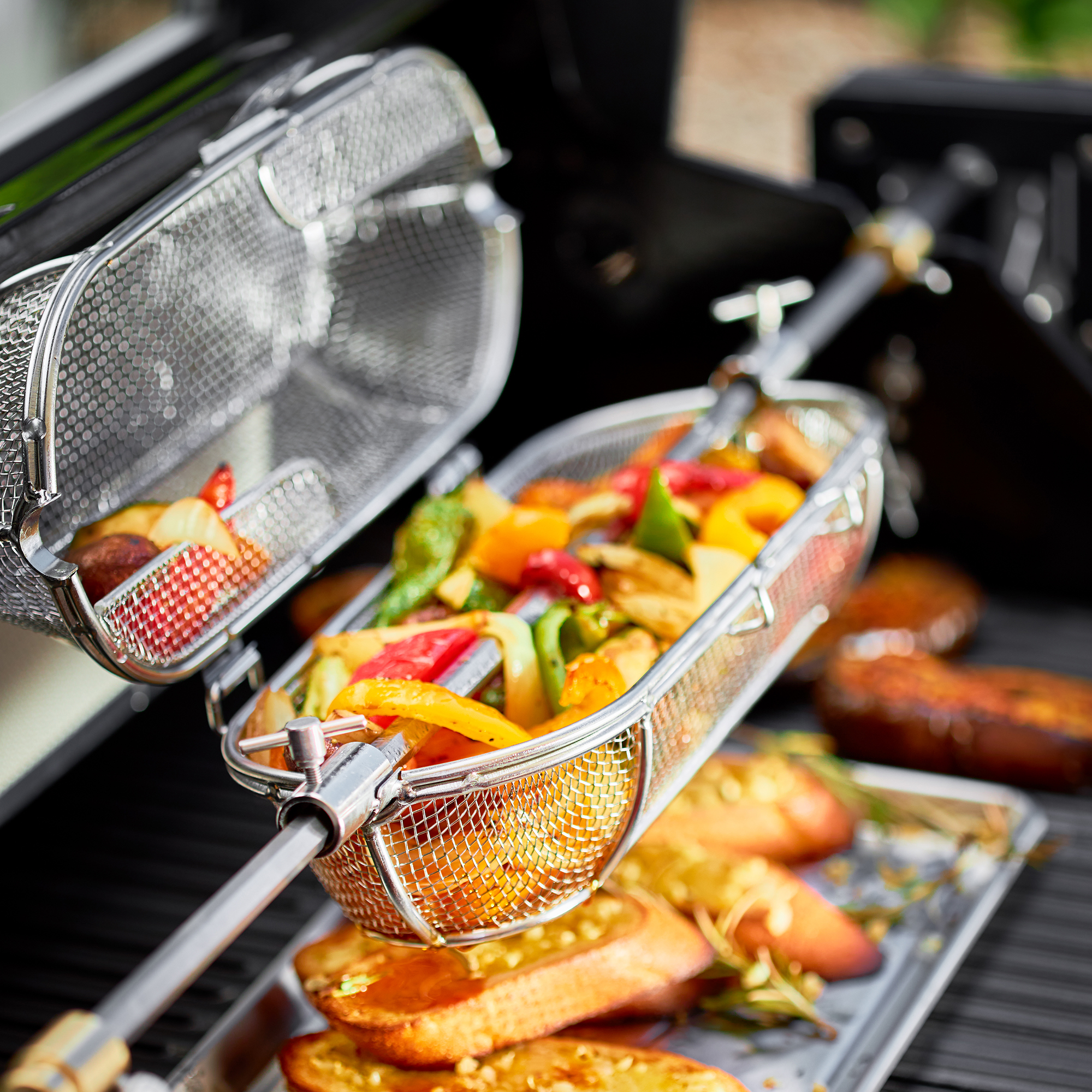 RÖSLE Drehspießkorb mit Gemüse Drehspießkorb mit buntem Gemüse und Grillgut auf einem Grillrost.
