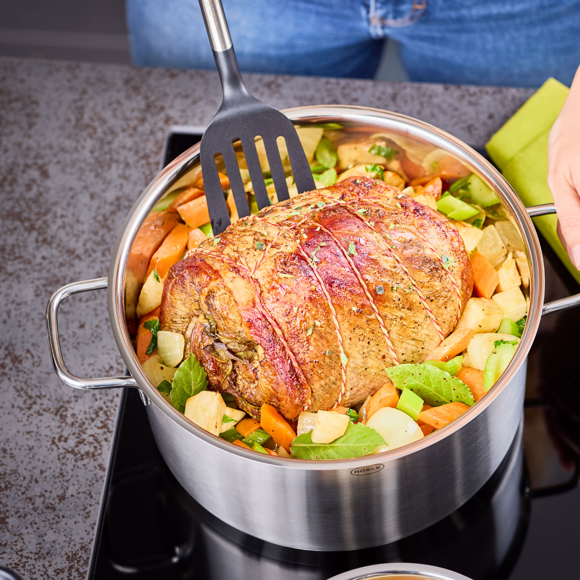 RÖSLE Gourmet-Set mit Braten und Gemüse Gourmet-Set: Ein Braten wird mit einem Pfannenwender aus einem Topf mit Gemüse gehoben.