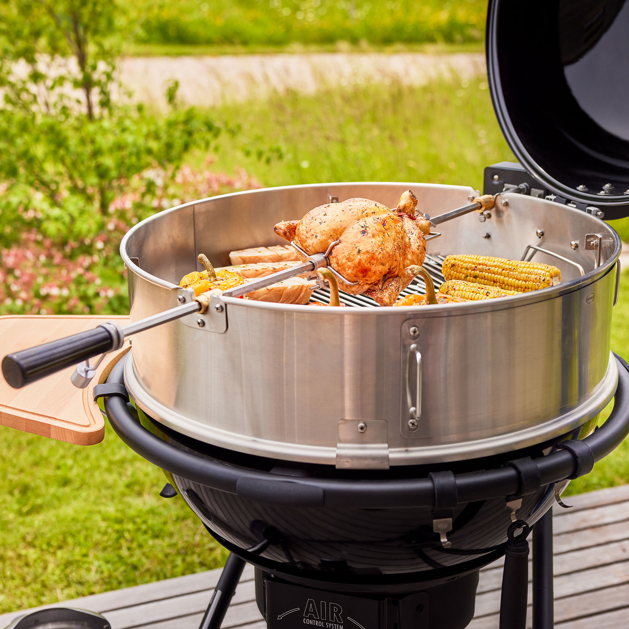 RÖSLE Holzkohle Kugelgrill No1 AIR F60 PRO Holzkohle Kugelgrill mit Grillrost, Hähnchen und Gemüse auf dem Grill, im Freien.
