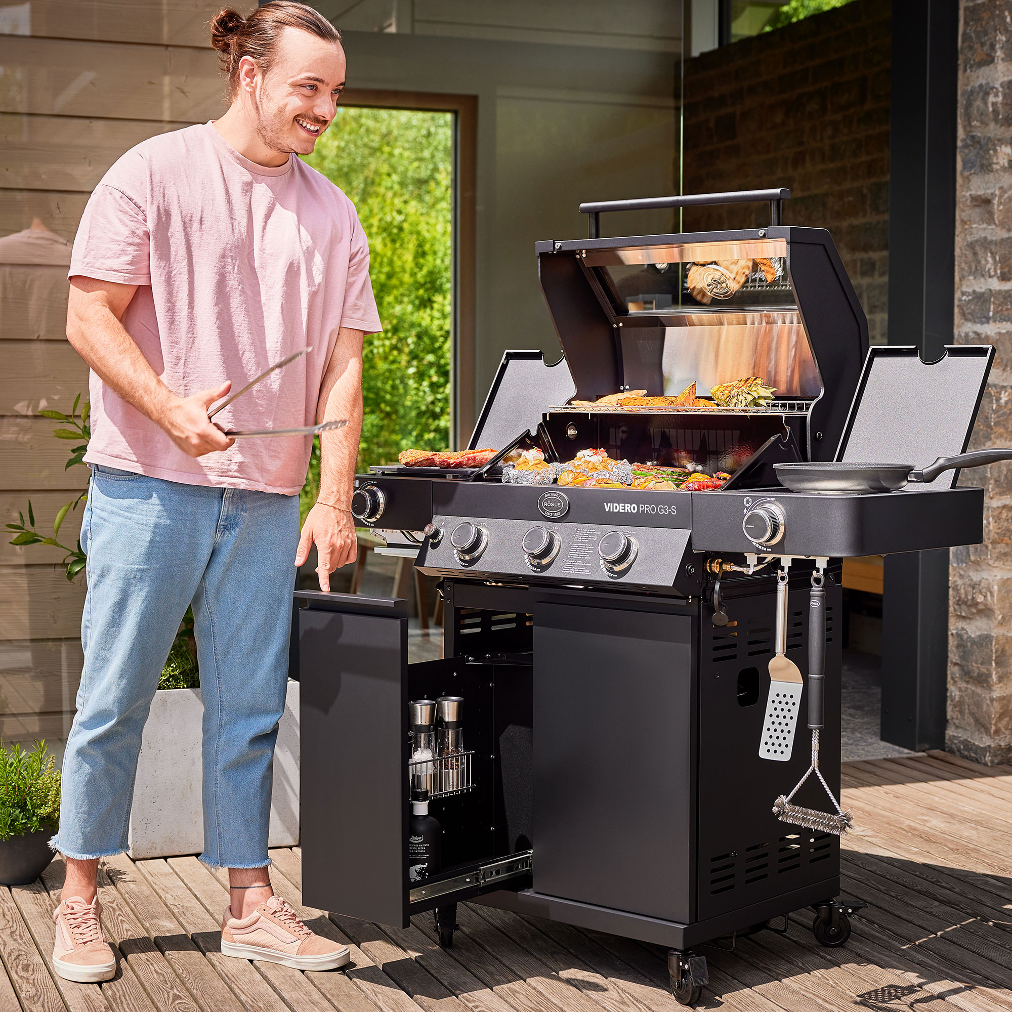 RÖSLE Gasgrill Videro G3-S PRO Gasgrill Videro G3-S PRO in Schwarz mit geöffnetem Deckel, Grillgut auf dem Rost, Mann mit...
